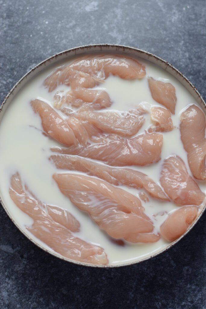 Chicken tenders in a bowl of milk.