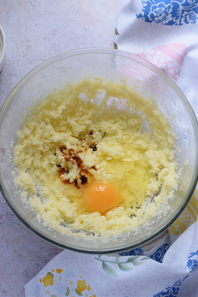 Butter and sugar with egg and vanilla in a glass bowl.