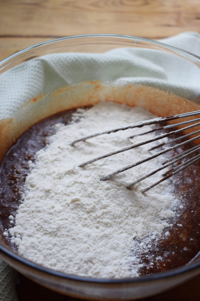 Adding flour to chocolate brownie batter.
