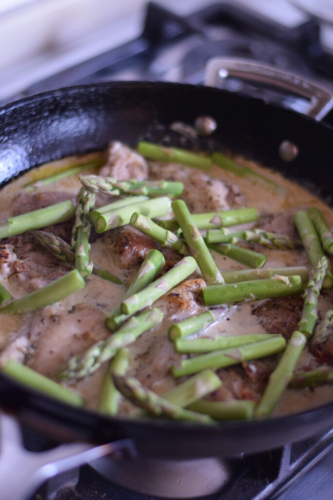 Adding fresh asparagus to a skillet.