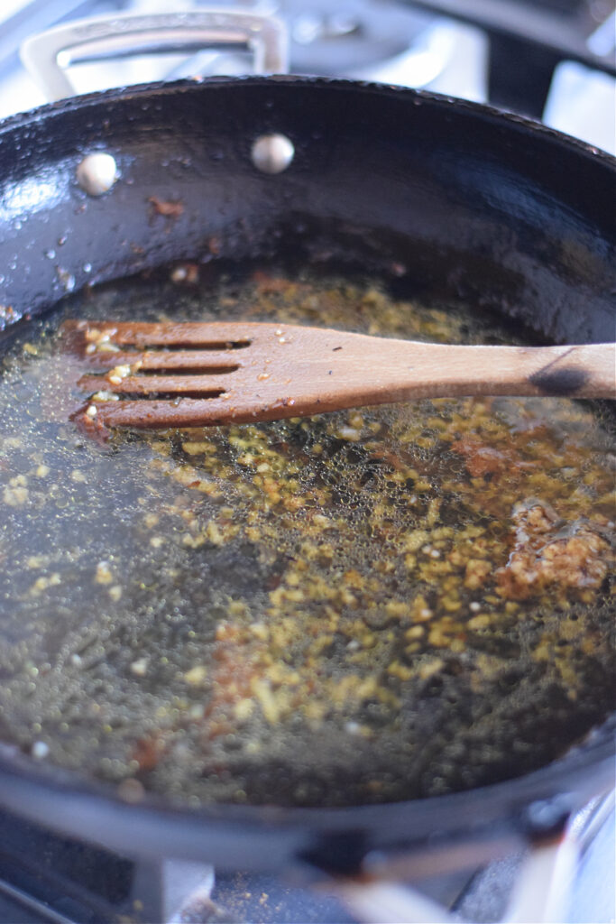 Adding chicken broth to a skillet.