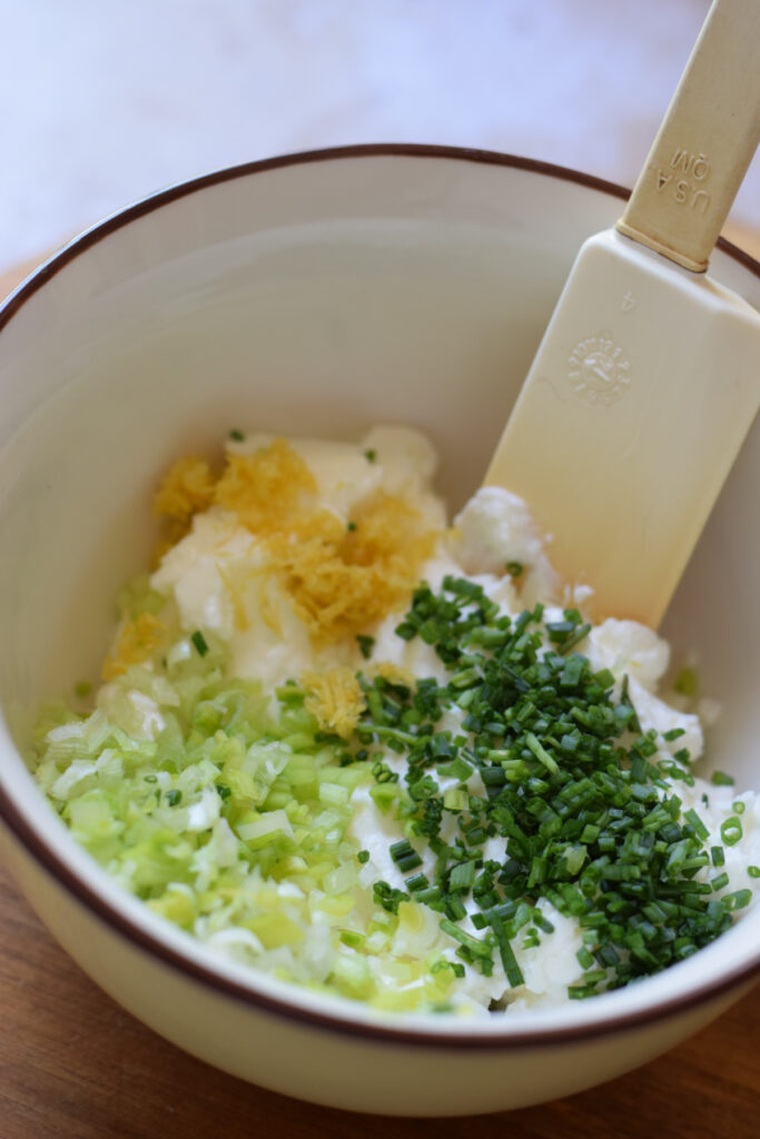 Cream cheese and herbs in a bowl.