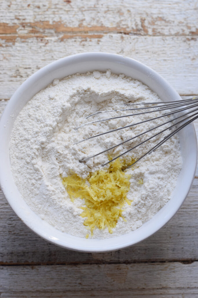 Flour and lemon zest in a glass bowl.
