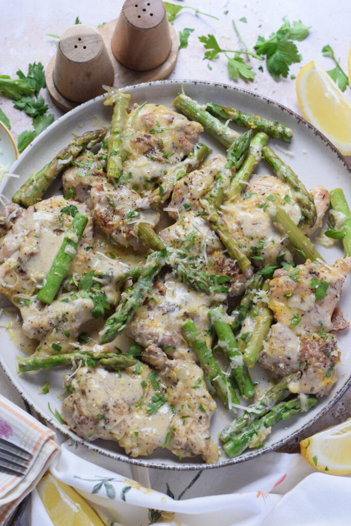 Lemon chicken thighs on a plate with asparagus.