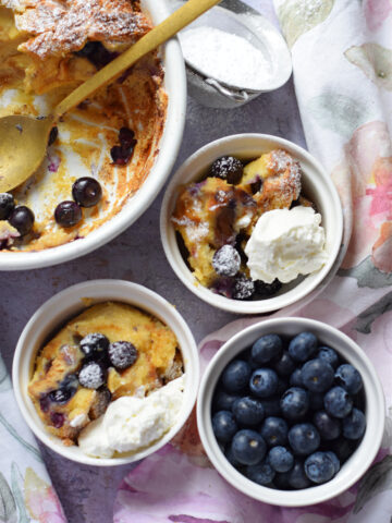 baked-blueberry-pudding-in-serving-bowls-image Blueberry bread pudding in white serving dishes.