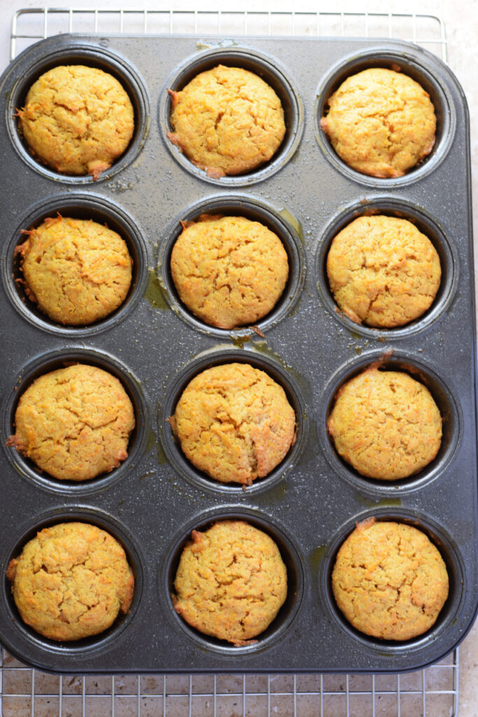 Baked carrot cake muffins in a muffin pan.