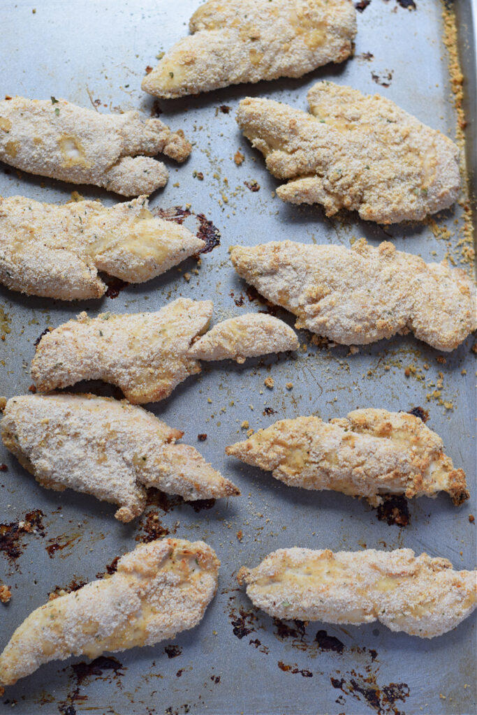 Baked chicken tenders on a baking tray.
