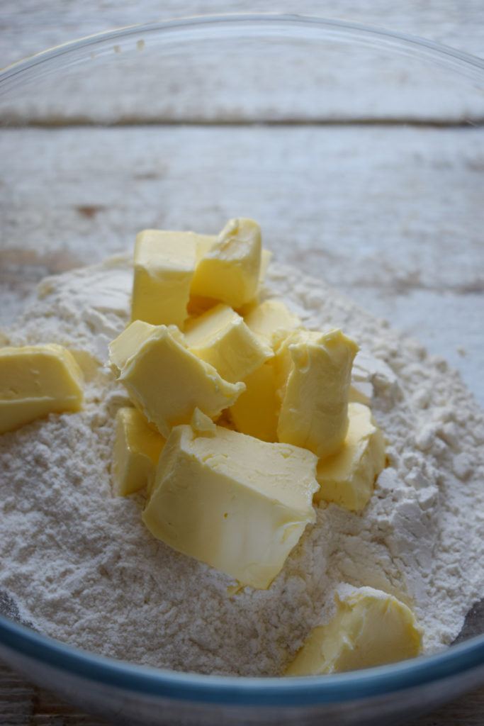 Butter nad flour in a bowl to make pastry.
