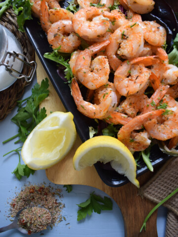 Baked cajun spiced shrimp with lemon wedges.