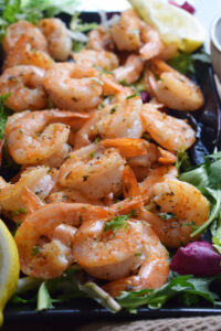 Cajun spiced shrimp on a plate with lemon wedges.
