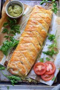 Pastry braid on a tray with tomatoes and pesto.