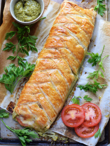 Pastry braid on a tray with tomatoes and pesto.