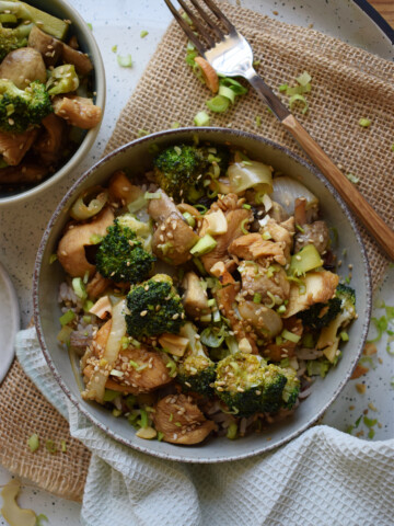 Chicken and broccoli stir fry in a bowl with a green napkin and fork.
