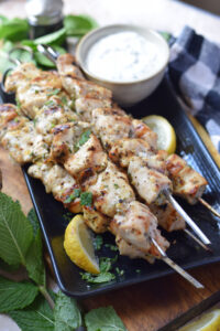 Chicken kebabs on a plate with a dip.