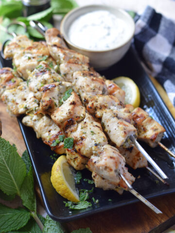 Chicken kebabs on a plate with a dip.
