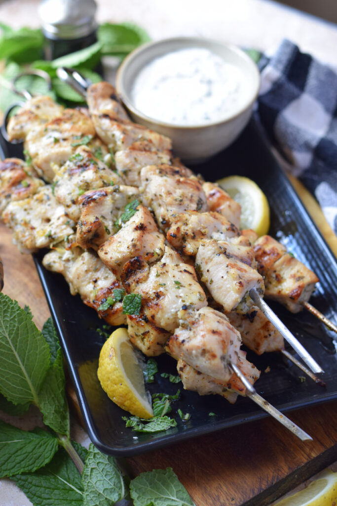Chicken kebabs on a plate with a dip.