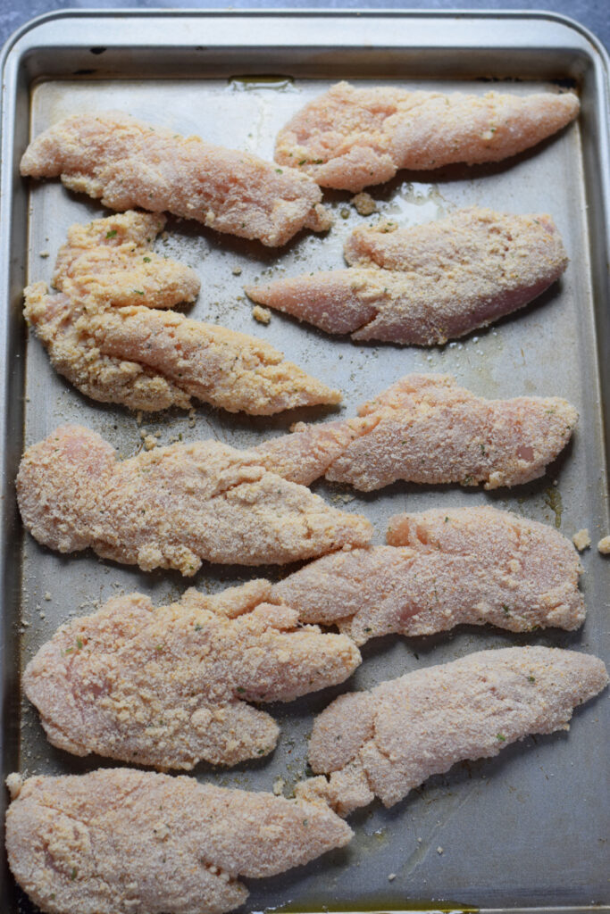 Chicken tenders on a baking tray.