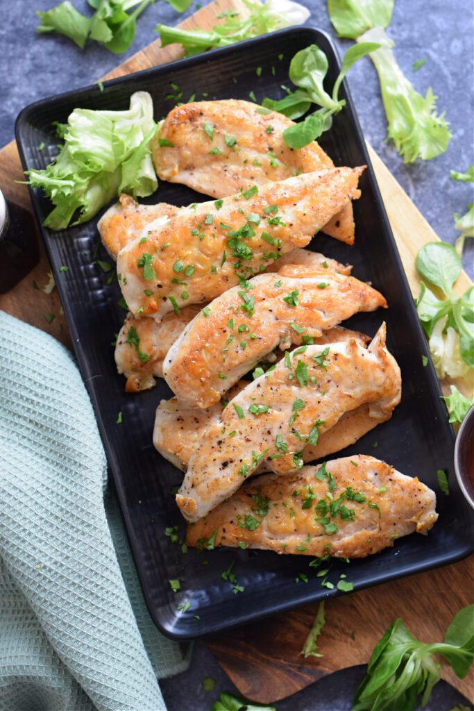 Chicken tenders on a black plate.