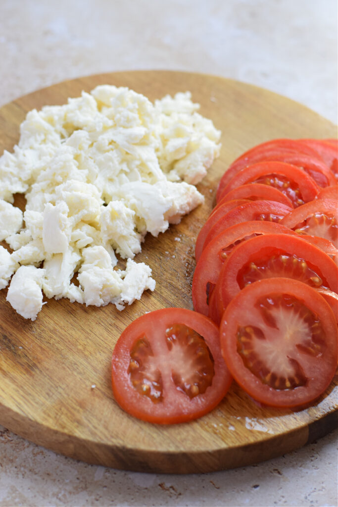Mozzarella cheese and sliced tomatoes on a wooden board.