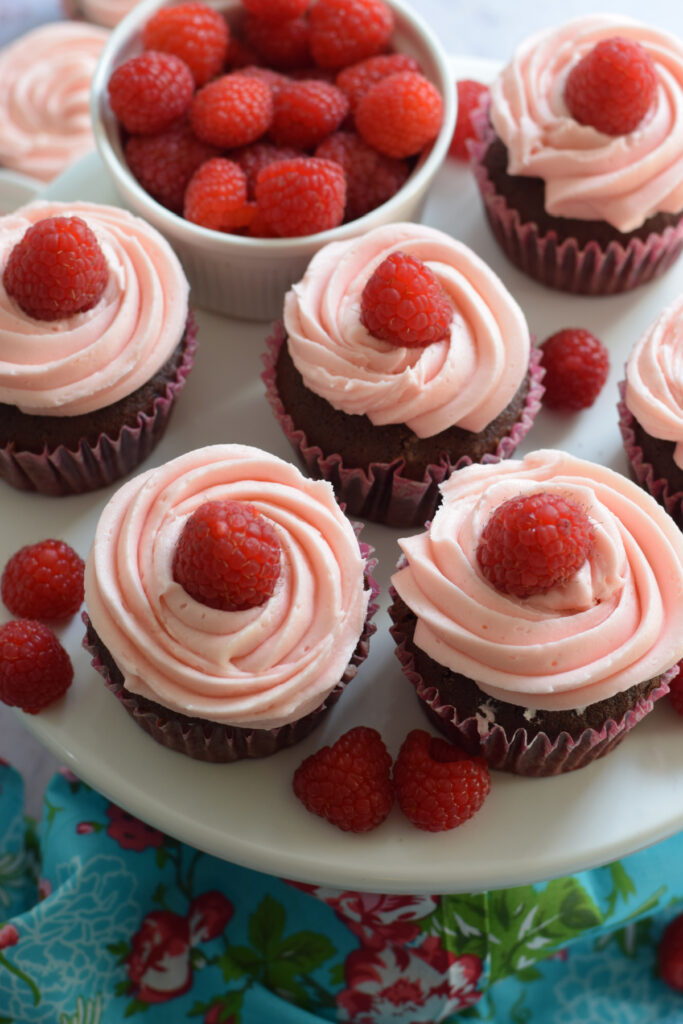 Pink frosted cupcakes on a white plate.