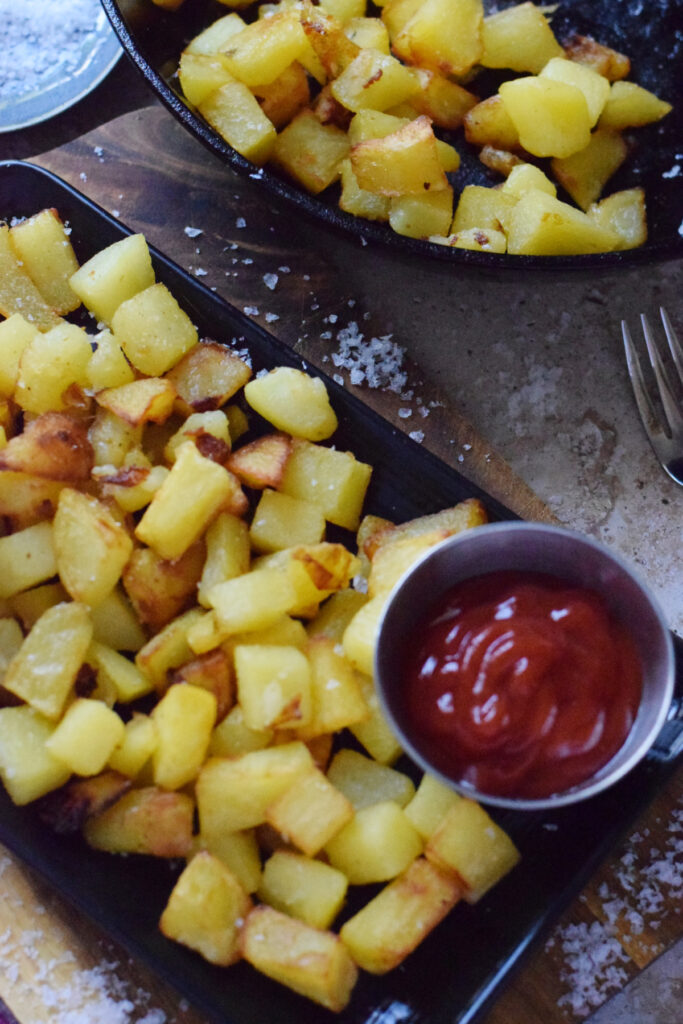 Country fries on a black plate.
