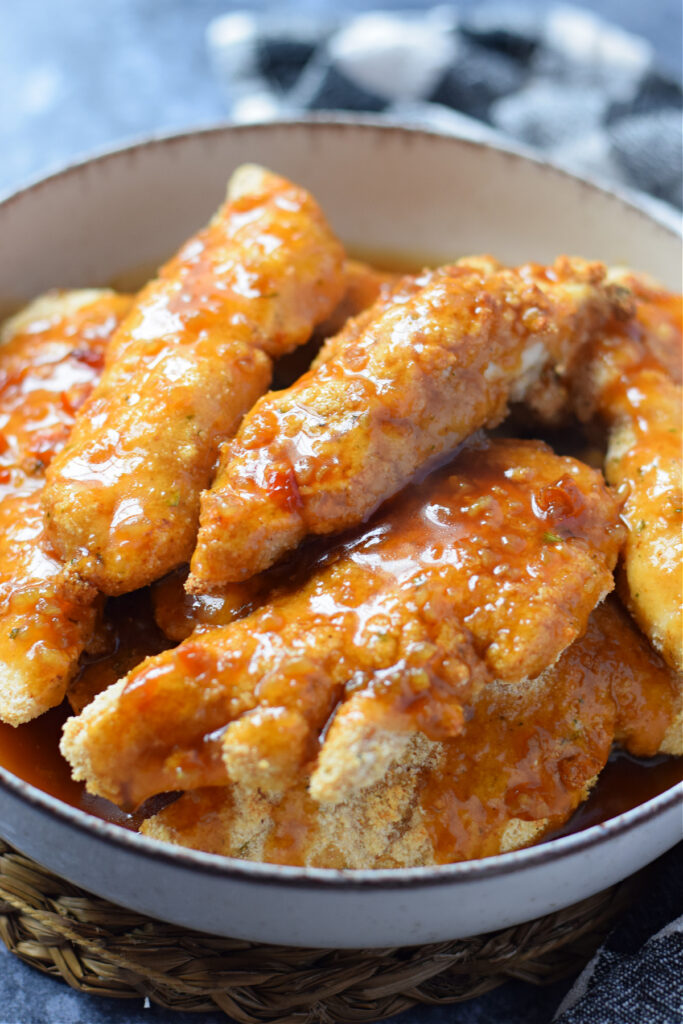 Close up of honey garlic chicken tenders in a bowl.