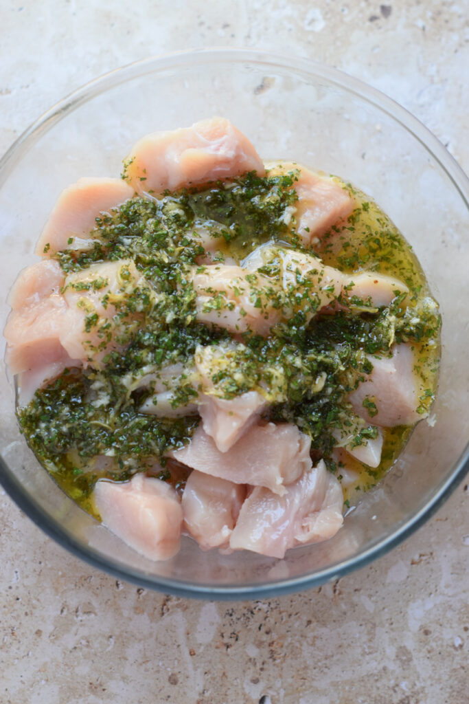 Marinade in a bowl with cubed chicken.