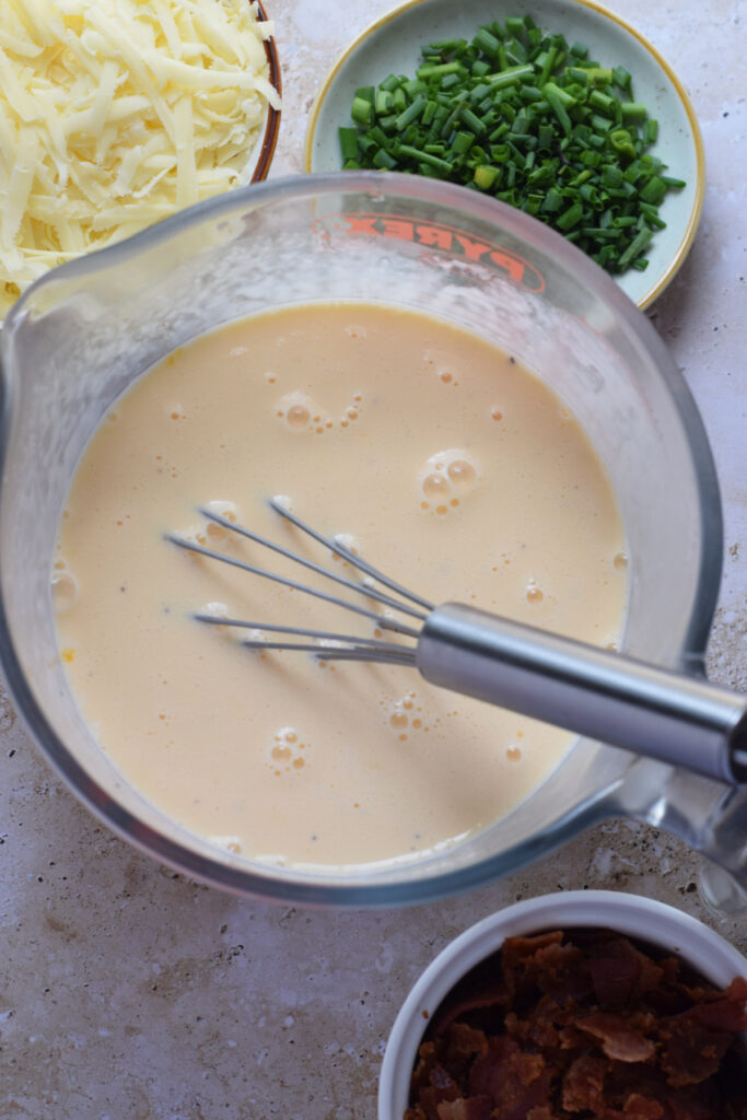 Whisked eggs and cream in a measuring cup.