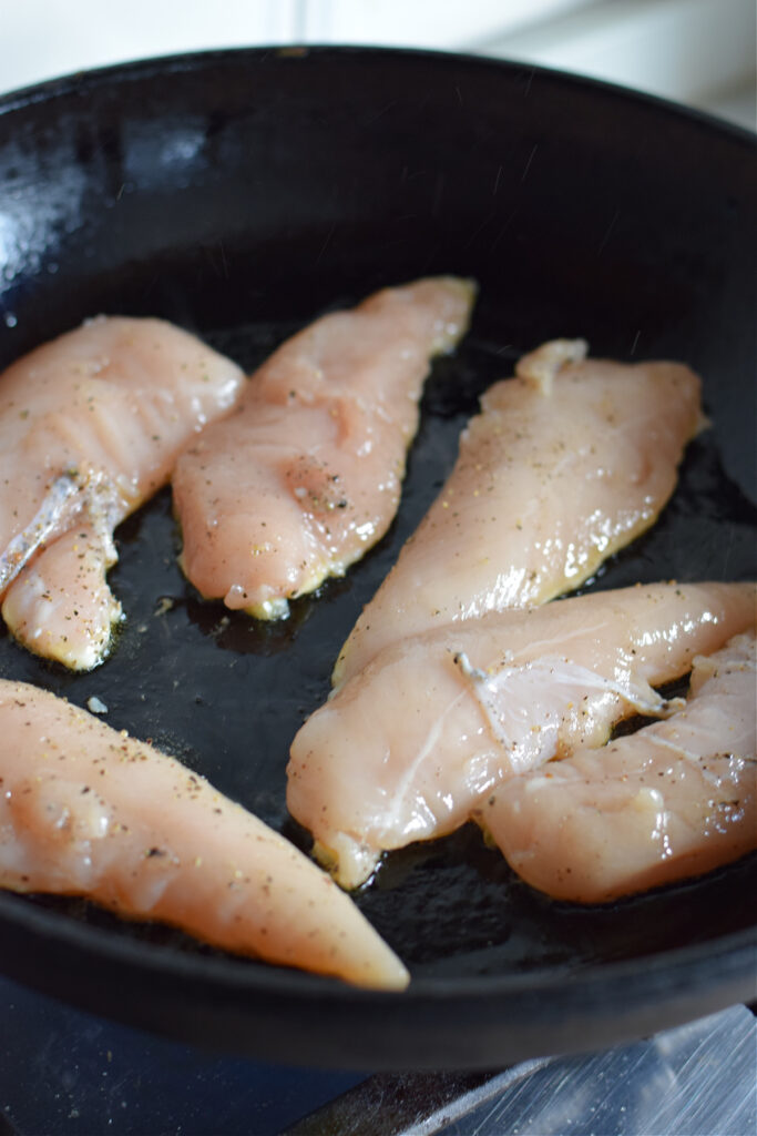 Cooking chicken tenders in a skillet.