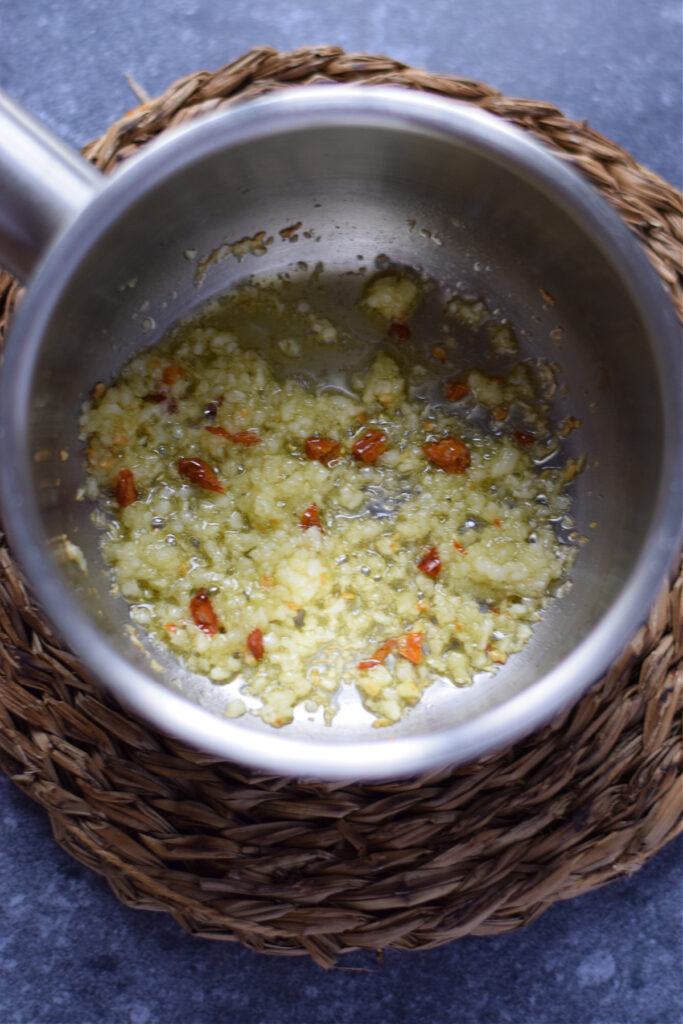 Cooking garlic and chillies in a small saucepan.