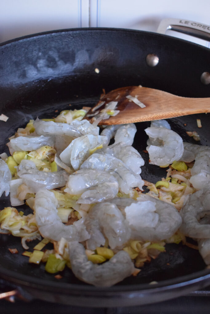 Adding shrimp to a skillet.