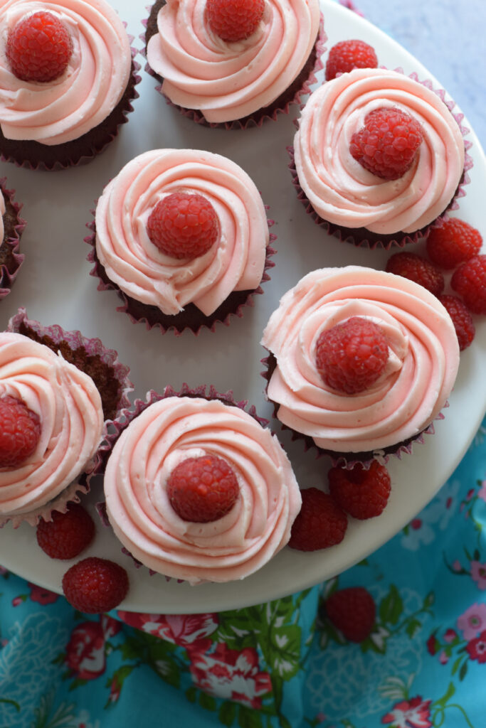 Pink frosted cupcakes on a white serving plate.