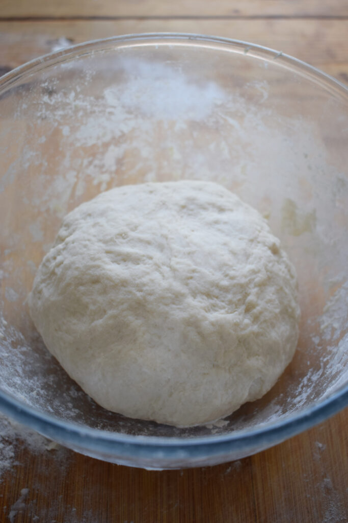 A dough ball in a glass bowl.