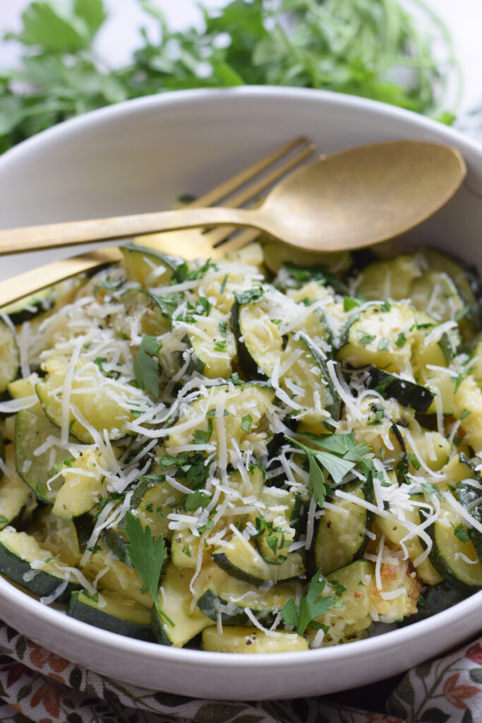 Parmesan topped zucchini in a white bowl.
