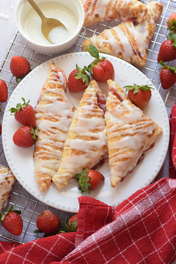 Puff pastry strawberry turnovers on a white plate.