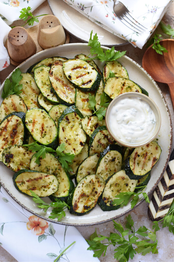 Zucchini on a white plate with a dip.