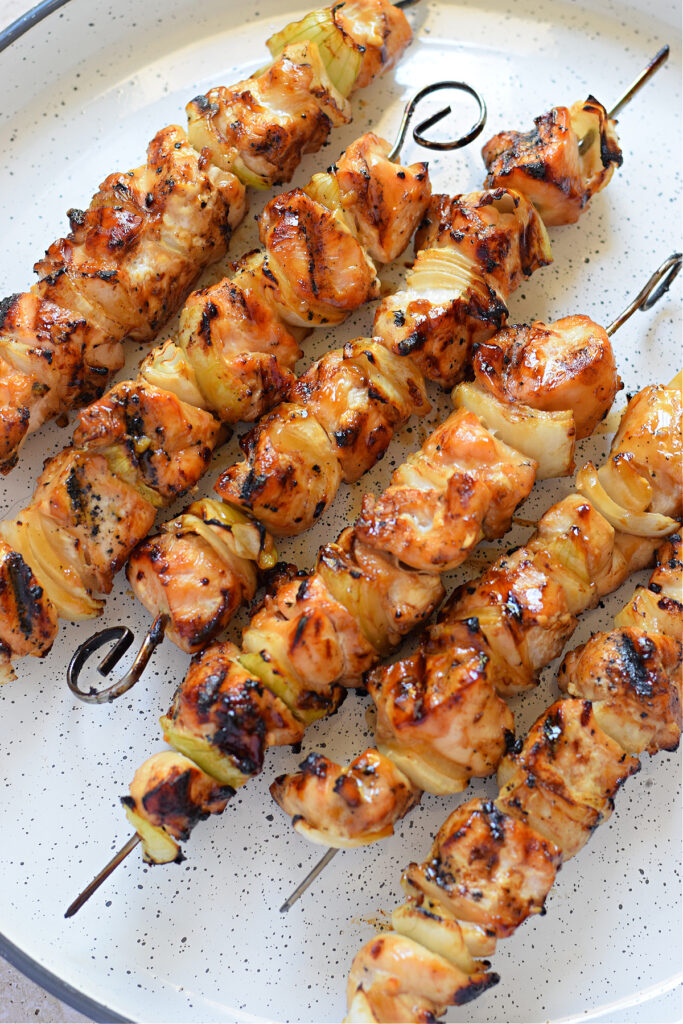 Chicken skewers on a white tray.
