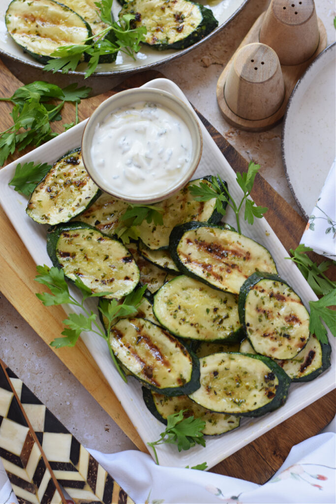 Grilled zucchini on a plate with a dip.