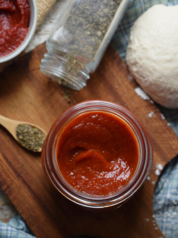 Homemade pizza sauce in a jar with dough.