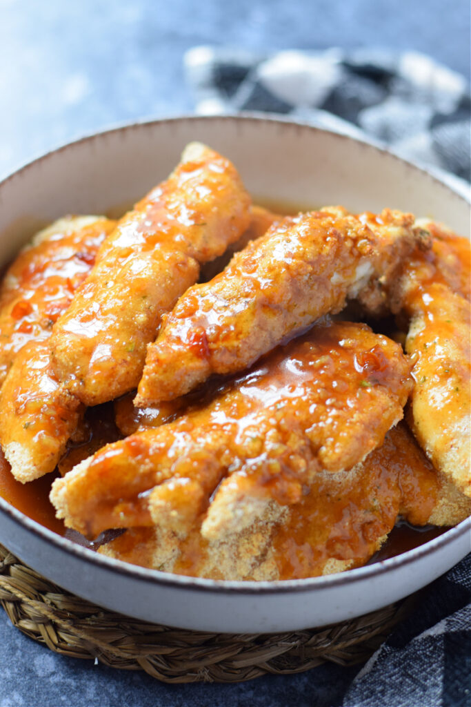 Chicken tenders coated in honey sauce in a bowl.