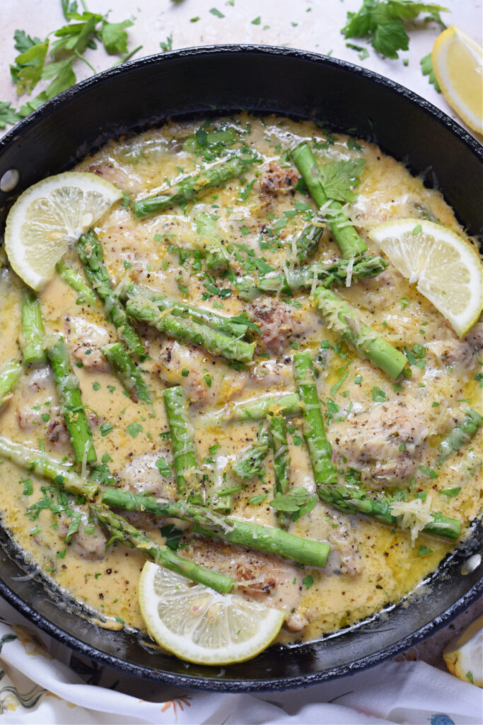 Lemon chicken and asparagus in a skillet.