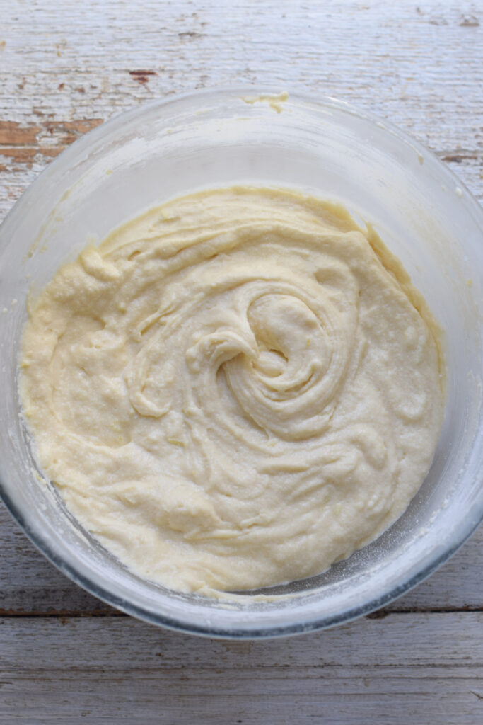 Mixed lemon muffin batter in a glass bowl.