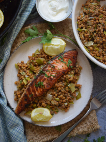Salmon with lentils and lemon wedges.