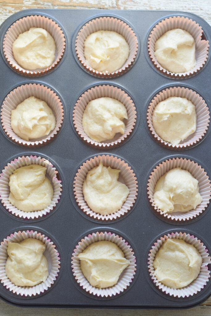 Lemon muffin batter in a muffin tray.