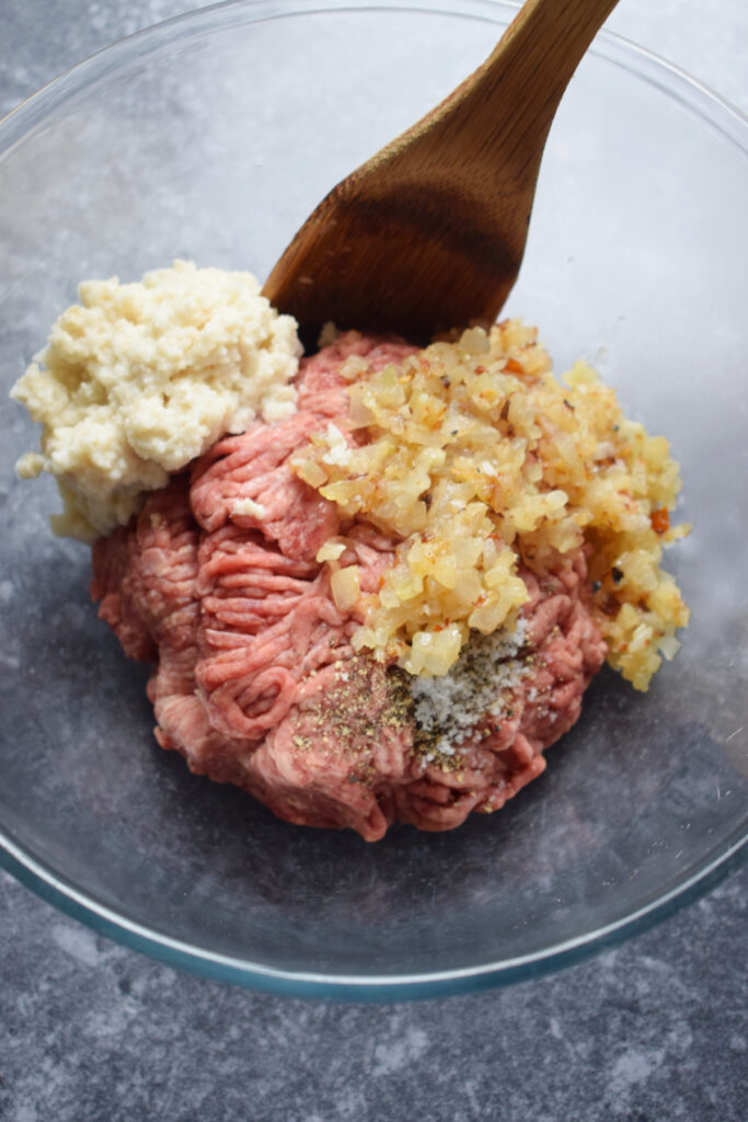 Adding ingredients to a bowl to make meatballs.