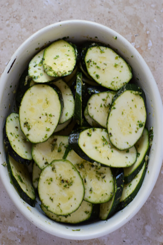 Marinated zucchini in an oval white bowl.
