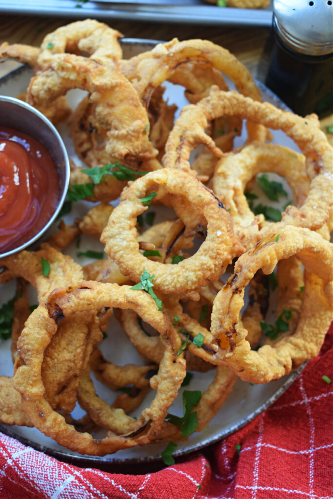 Crispy onion rings on a plate with ketchup in a small dish.