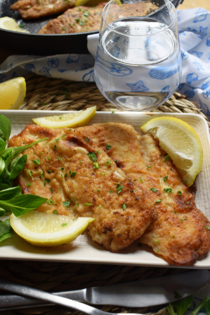 crispy fried fish on a plate with a glass of water