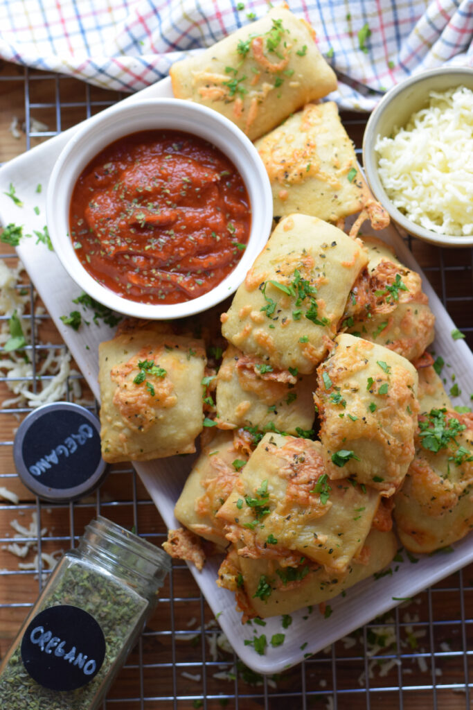 Pizza pockets on a tray with a dipping sauce.
