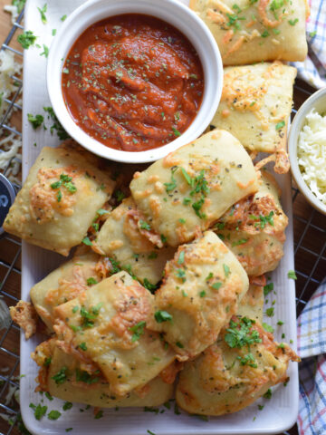 pizza-pocket-bites-on-a-white-plate Pizza pocket bites on a plate with a dipping sauce.